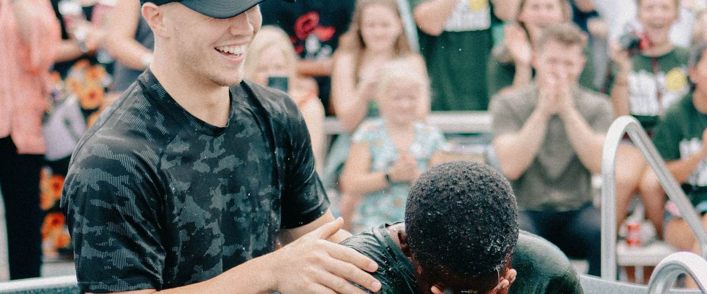 Two men smiling in the water during an outdoor baptism