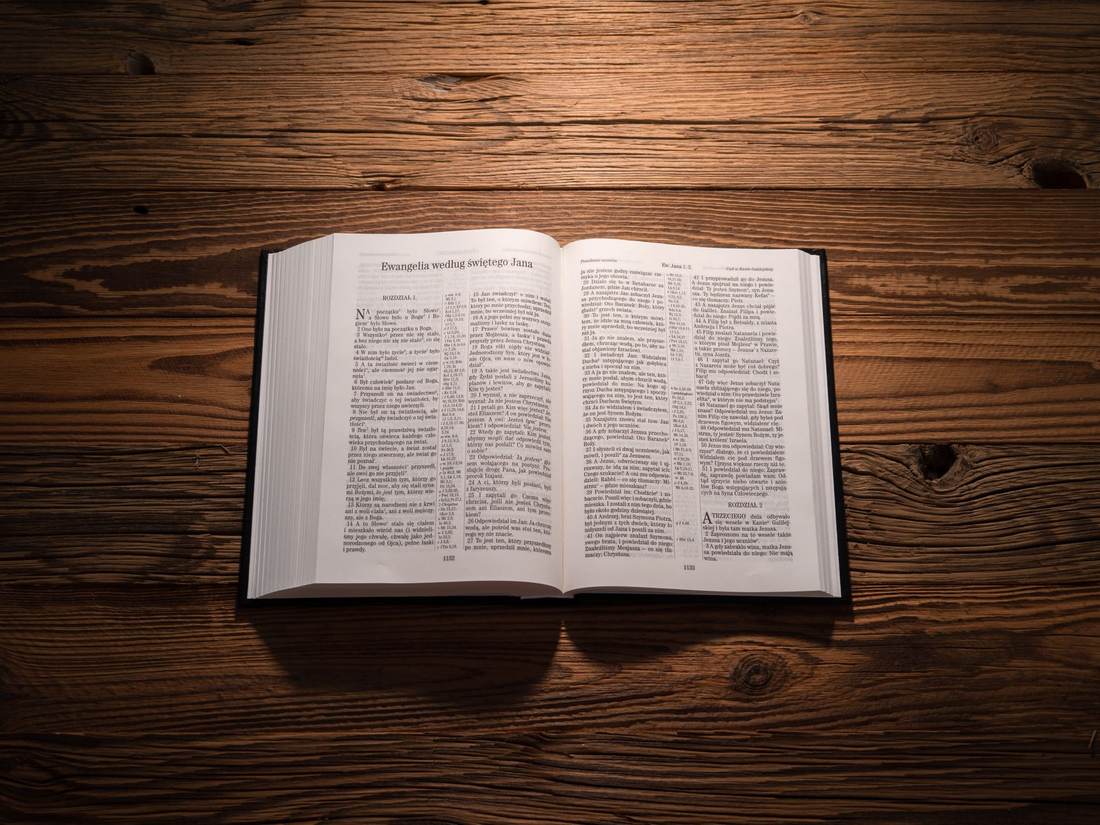 An open Bible lying on a dark wooden table