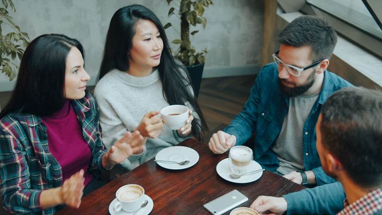 Friends talking together over coffee around a table