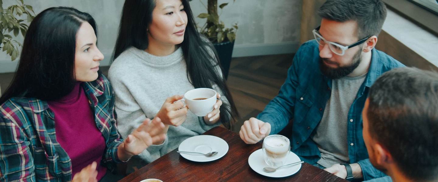 Friends talking together over coffee around a table