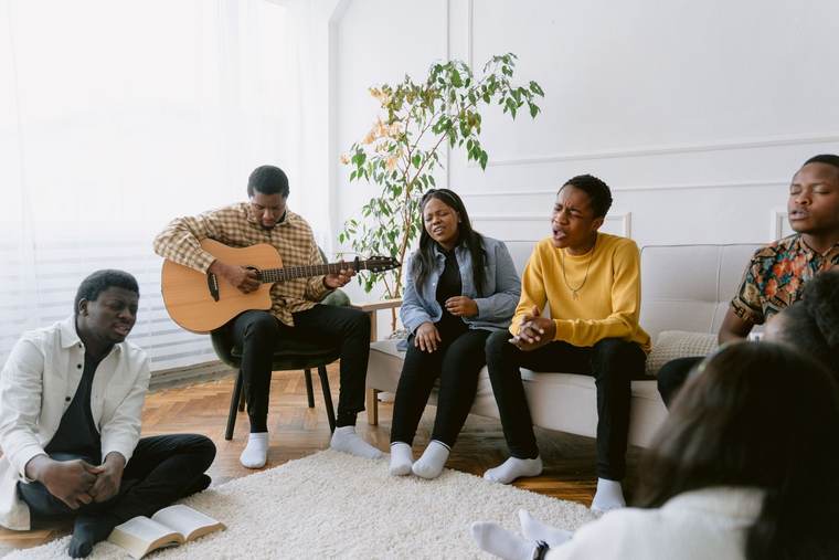A small group singing together with a guitar in a living room