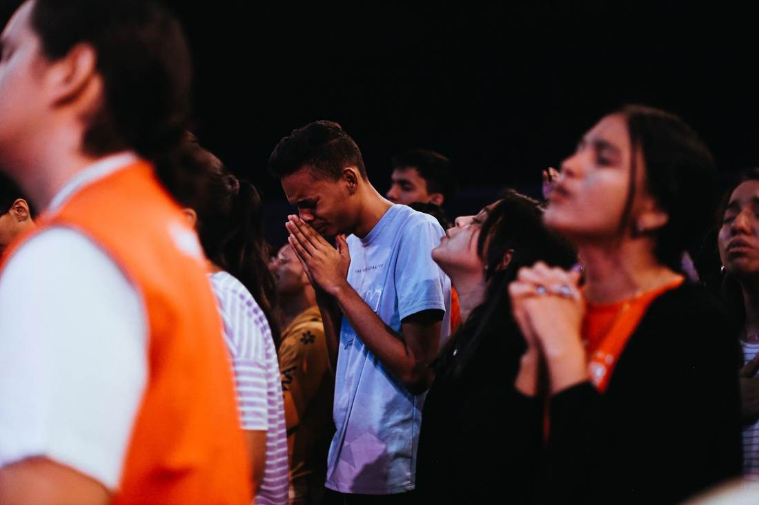 Young adults praying with their eyes closed during a church gathering