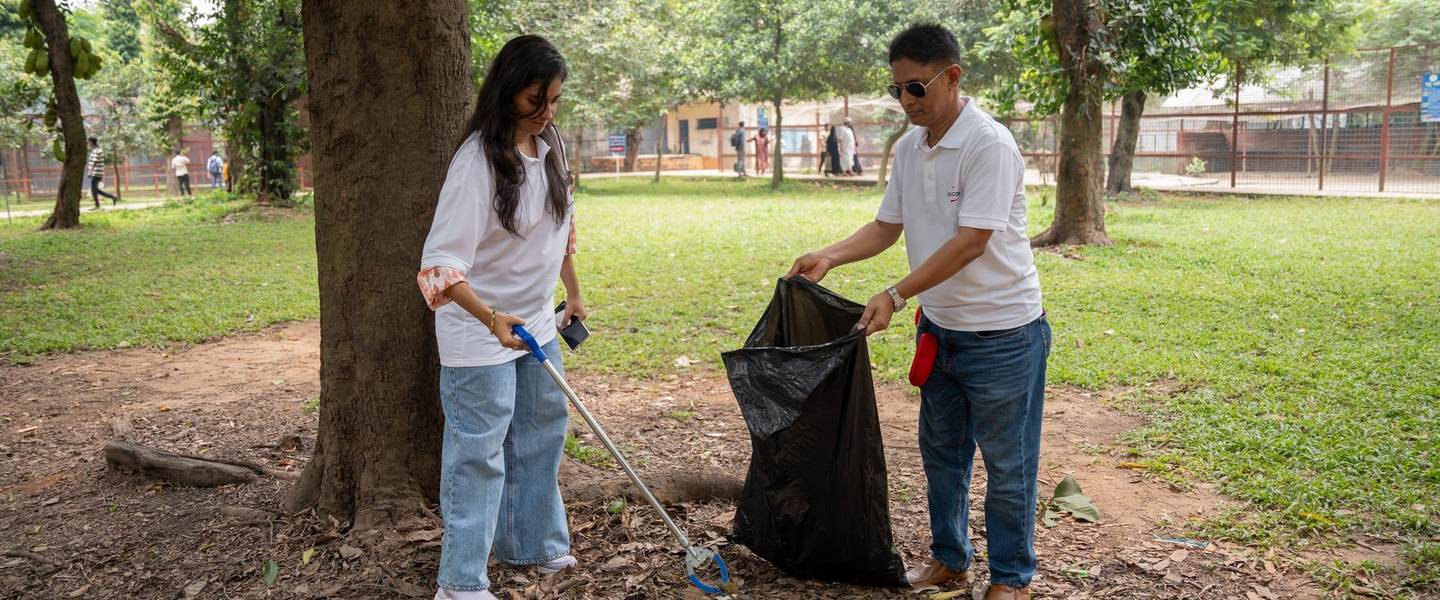 Two volunteers picking up litter in a park