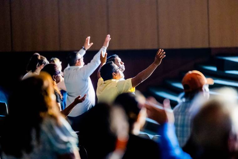 A congregation raising their hands in worship during a contemporary church service