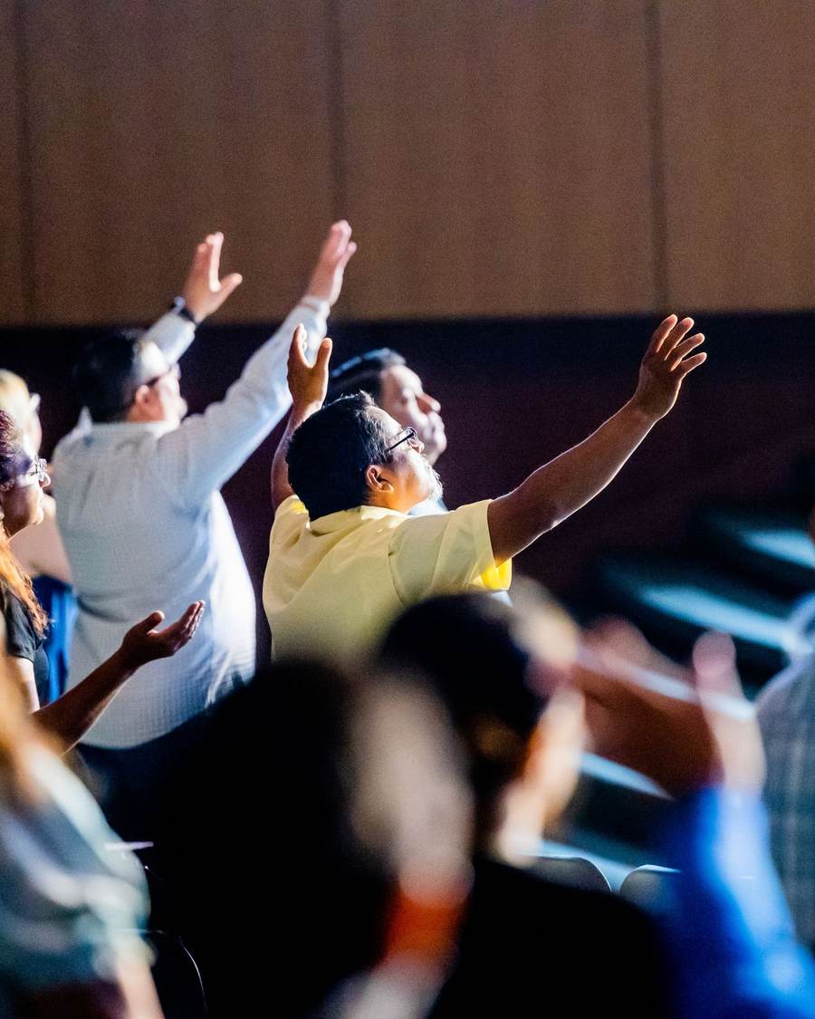 A congregation raising their hands in worship during a contemporary church service