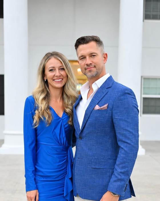 Pastor Filipp Timoshenko and his wife standing outside a white building with columns