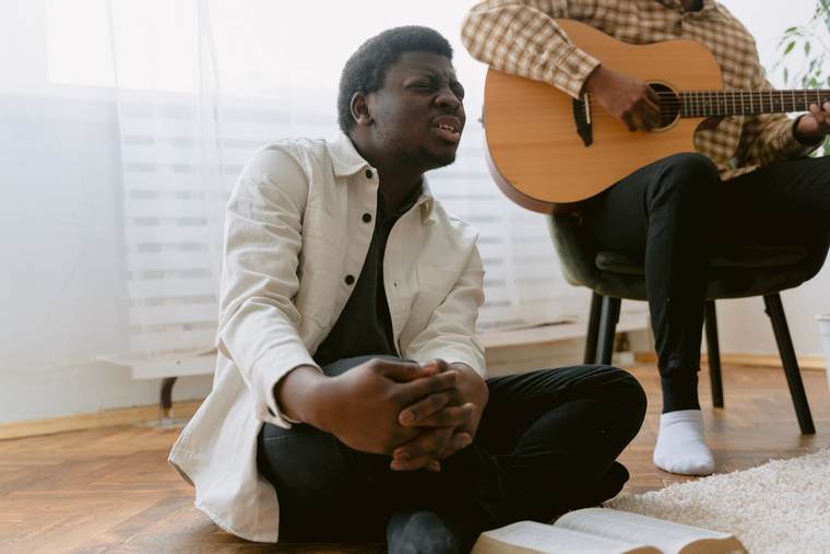 A young man singing in worship beside a guitarist